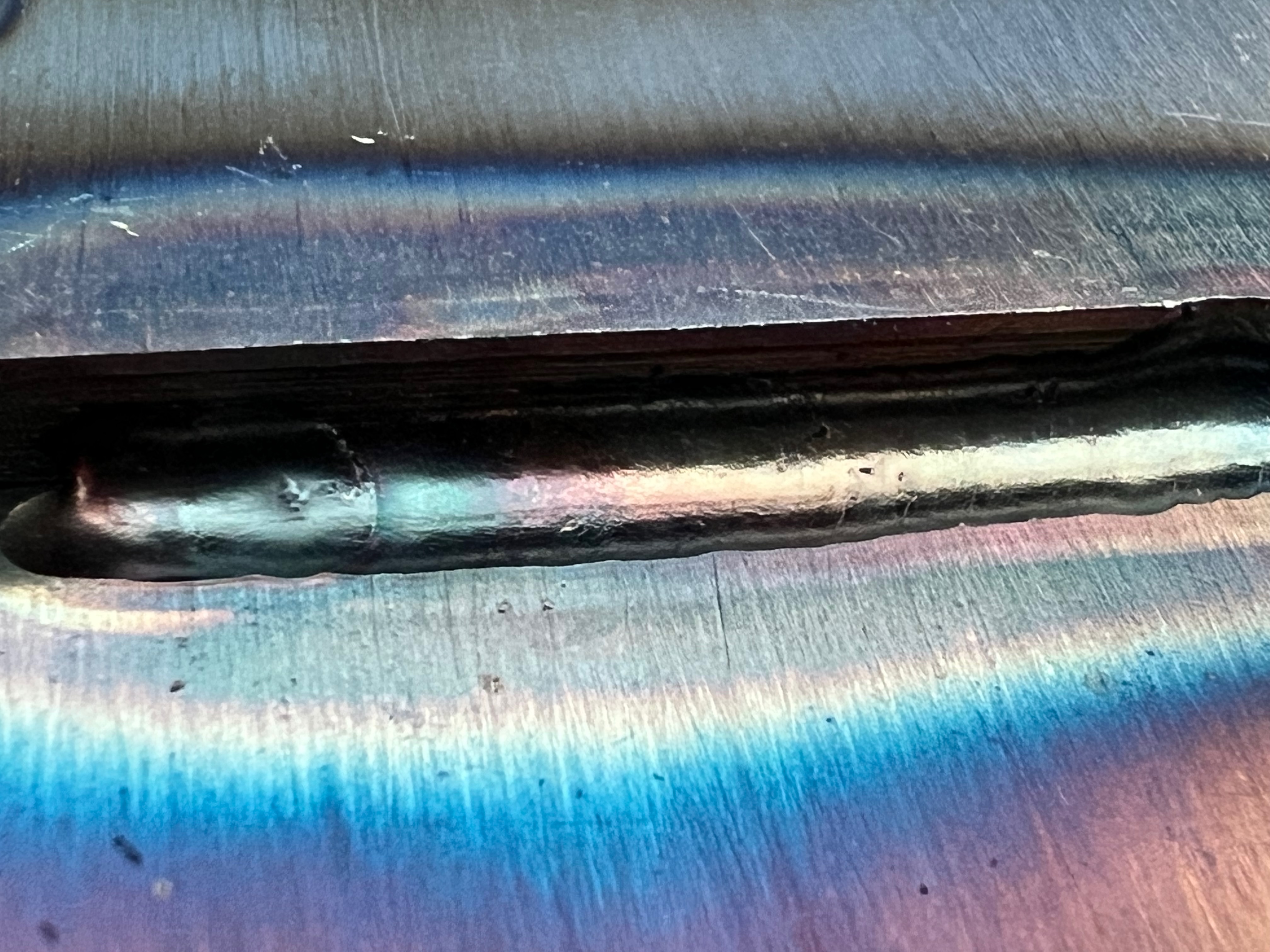 Professional TIG weld showing perfect stack-of-dimes pattern with heat coloration